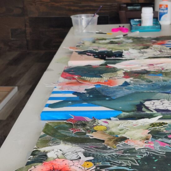 work in progress. the image shows mixed media paintings on the work desk in a studio