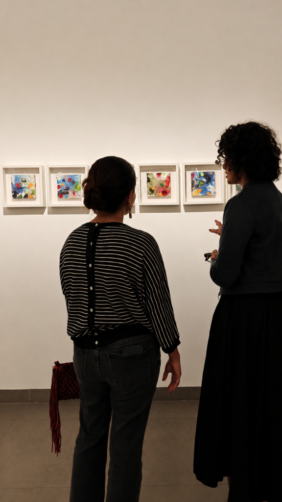 Artist Asma Kazi in conversation with a visitor during the Cartographies of Mischief Exhibition at Akar Prakar. They are looking at Cosmic lilies by Asma Kazi