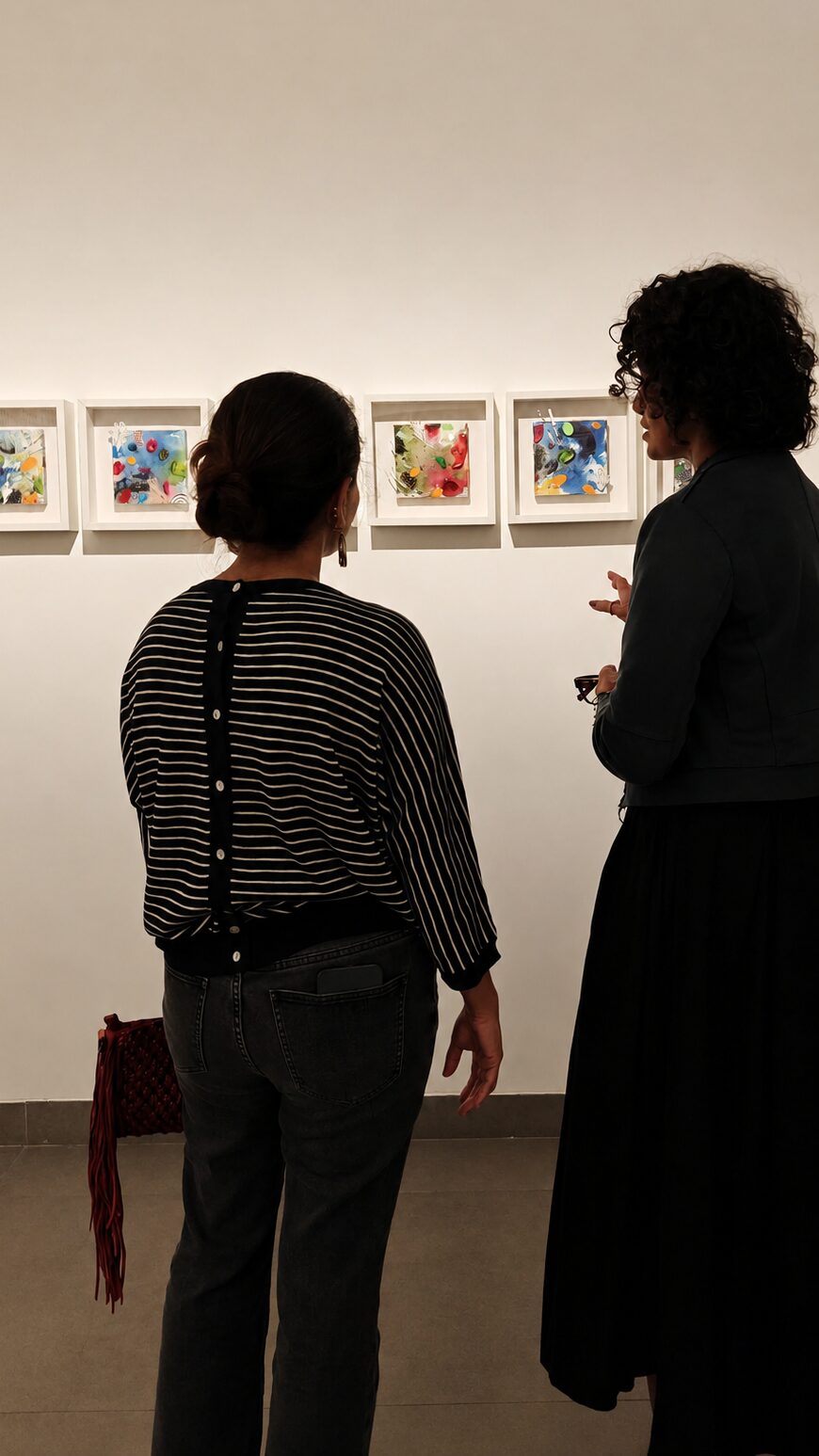 Artist Asma Kazi in conversation with a visitor during the Cartographies of Mischief Exhibition at Akar Prakar. They are looking at Cosmic lilies by Asma Kazi